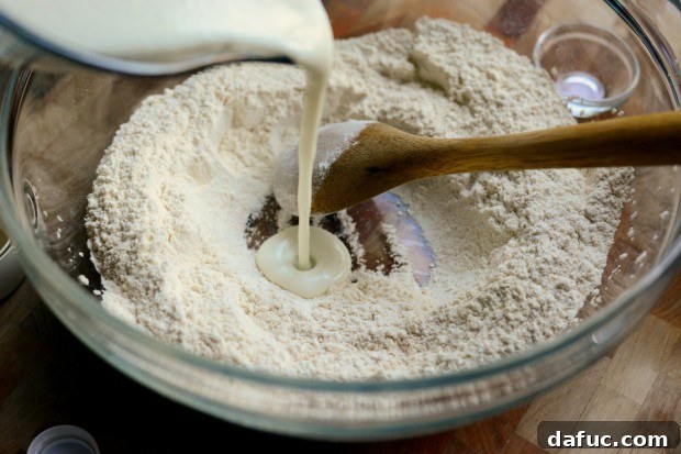 Pillowy Naan Perfection at Home 15 Yogurt and yeast liquid being poured into the well of dry ingredients.