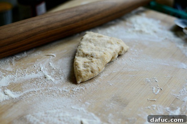 Pillowy Naan Perfection at Home 26 A single piece of naan dough being rolled out thin with a floured rolling pin.