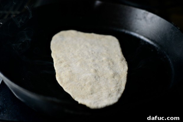 Pillowy Naan Perfection at Home 29 Melted butter being brushed onto a hot cast iron skillet before adding naan dough.