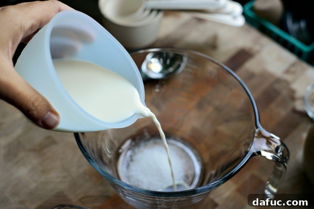 Pillowy Naan Perfection at Home 5 Warm milk and water poured over sugar in a bowl, ready for yeast activation.