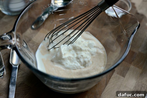 Pillowy Naan Perfection at Home 10 Yogurt being added to the bowl containing the activated yeast mixture.