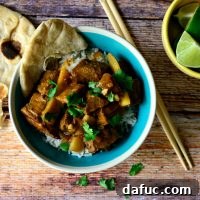 Spicy Thai Red Curry Beef 2 A vibrant bowl of Thai Red Curry Beef with jasmine rice, garnished with fresh cilantro and a lime wedge.