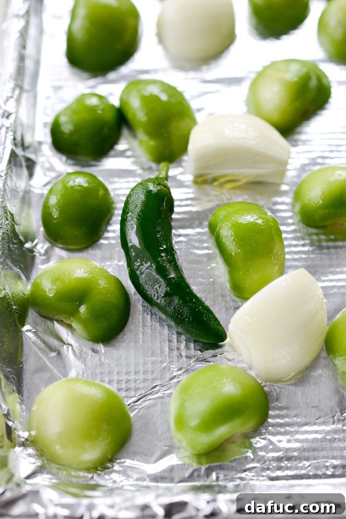 Zesty Tomatillo Avocado Salsa 6 Tomatillos, Jalapeno, and onion on a lined sheet pan before broiling.