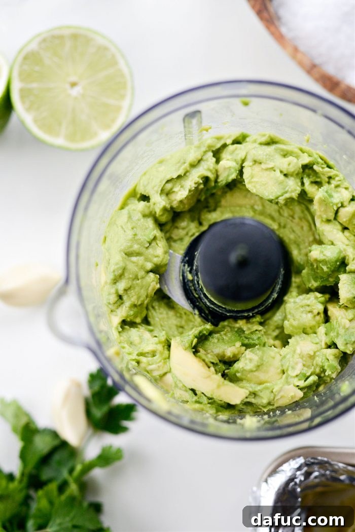 Zesty Tomatillo Avocado Salsa 9 Adding avocado to a food processor and pulsing.