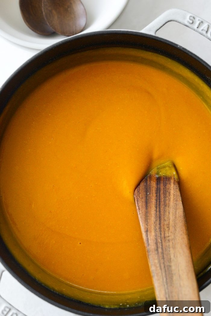Vibrant Sweet Potato Tomatillo Bisque 17 Sweet potato tomatillo bisque being stirred in a Dutch oven
