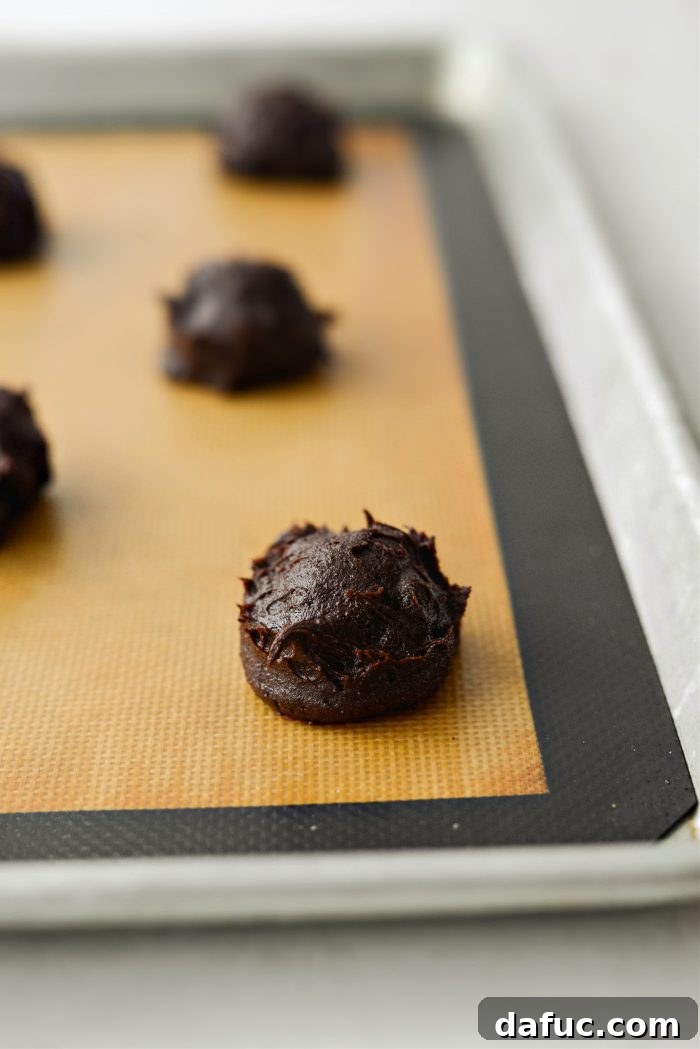 Decadent Merlot-Infused Dark Chocolate Cookies 17 Scoops of Double Dark Chocolate Merlot cookie dough arranged on a silicone mat-lined baking pan.