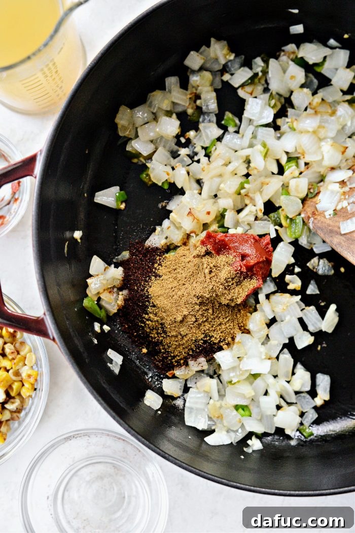 Tomato paste, ancho chili powder, and ground cumin added to sautéed aromatics
