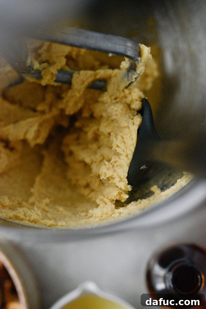 A rubber spatula scraping down the sides of the mixing bowl to ensure all ingredients are combined.
