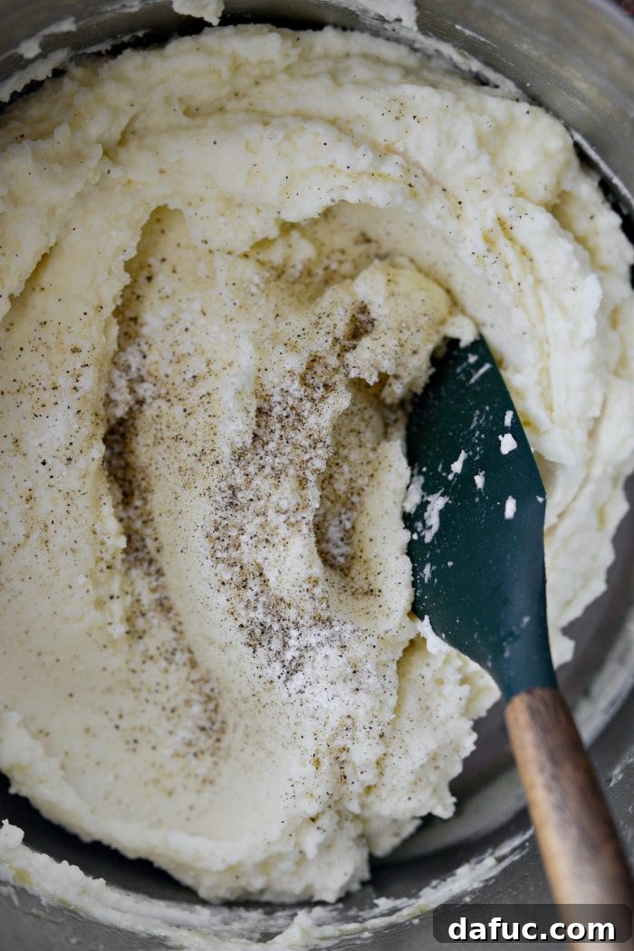 Heirloom Mashed Potatoes 18 season with salt and pepper - hands seasoning mashed potatoes with salt and pepper