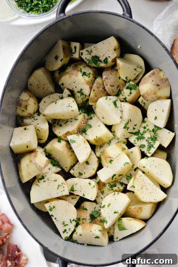 Dublin's Hearty Comfort Coddle 14 Potatoes being layered into the empty Dutch oven and seasoned with salt, pepper, and parsley.