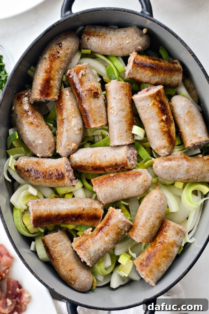 Dublin's Hearty Comfort Coddle 15 Onions, leeks, and sliced sausages being added as the next layer in the Dutch oven.