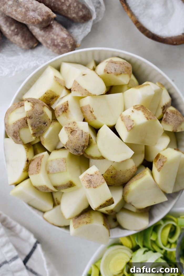 Dublin's Hearty Comfort Coddle 6 Roughly peeled russet potatoes being cut into large pieces for Dublin Coddle.