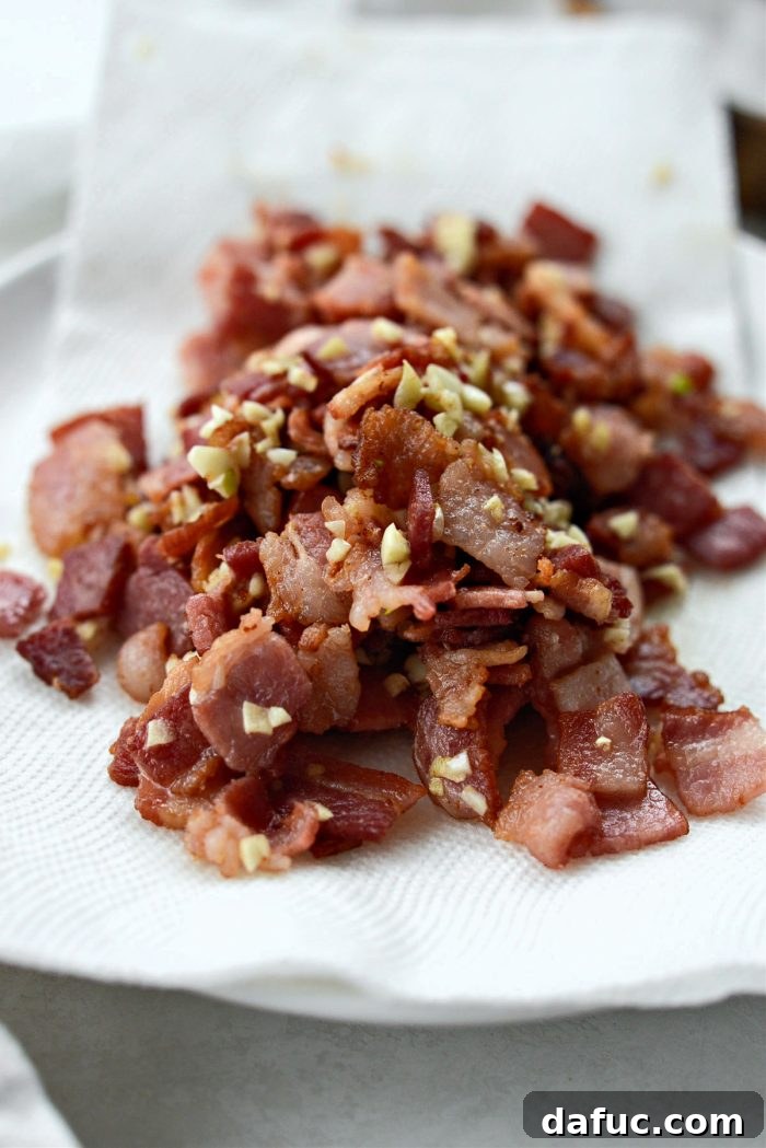Dublin's Hearty Comfort Coddle 10 Crispy bacon and cooked garlic removed from the pan and resting on a paper towel-lined plate.