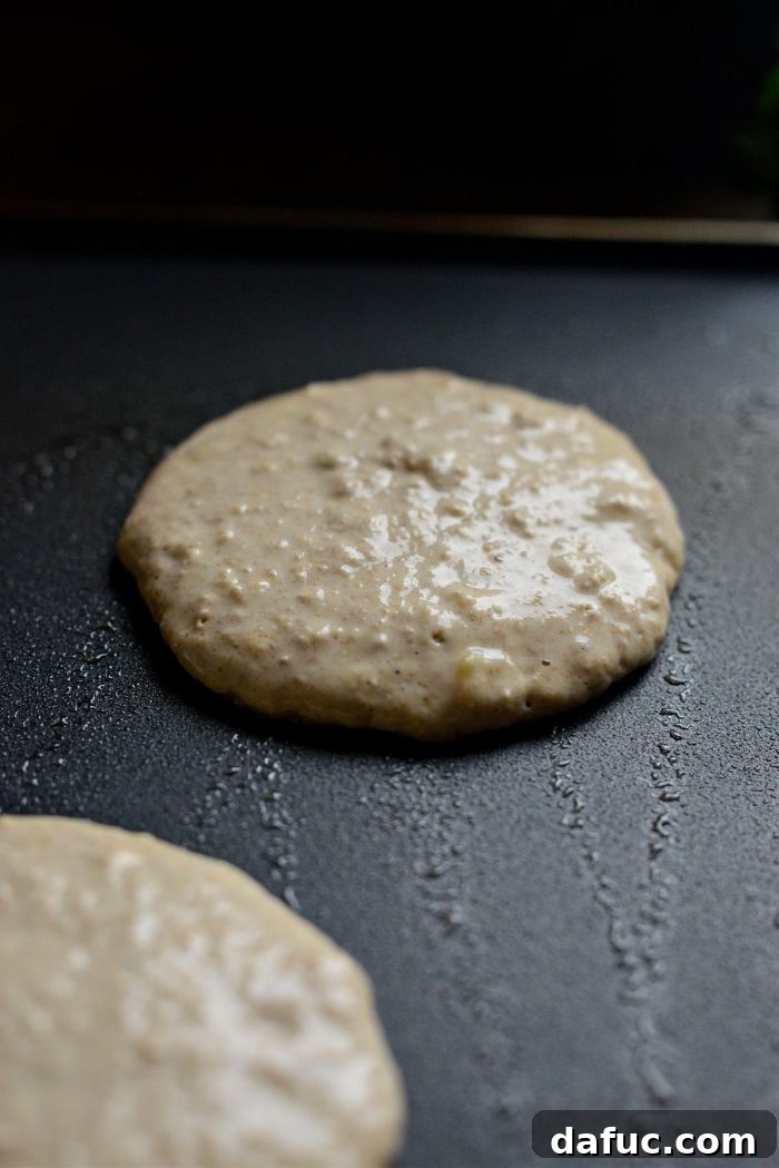 Pancakes cooking on a griddle, showing bubbles forming