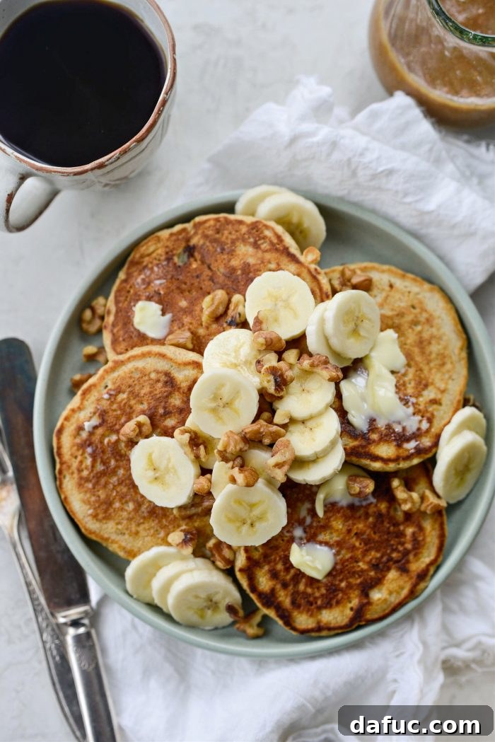 Stacked pancakes topped with butter, bananas, and walnuts