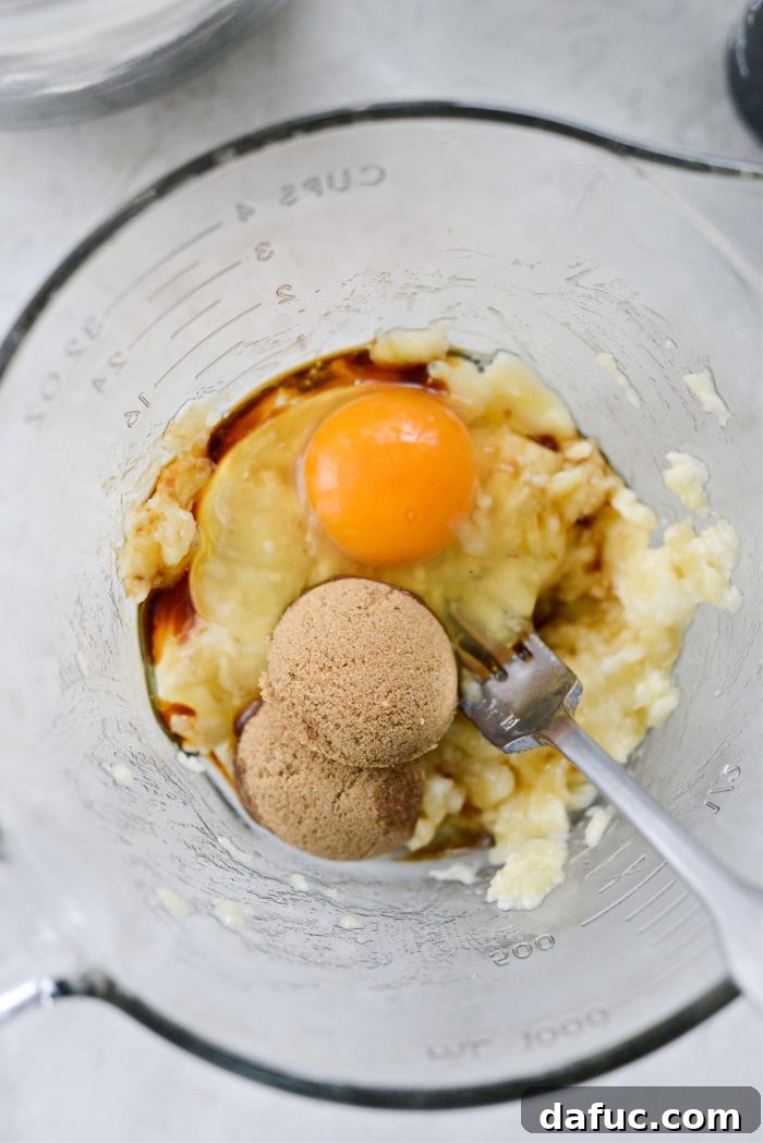 Egg, vanilla, brown sugar, and mashed banana in a bowl