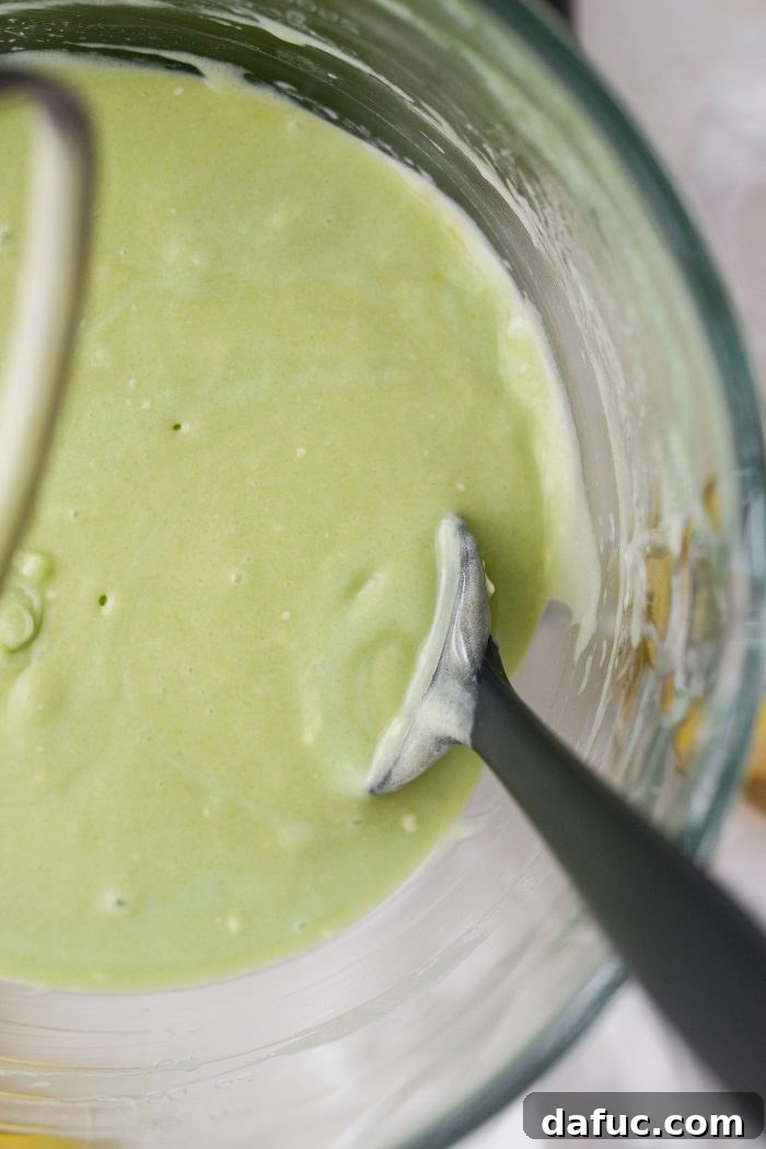 Scraping down the sides and bottom of the mixing bowl with a rubber spatula to ensure all ingredients are incorporated.