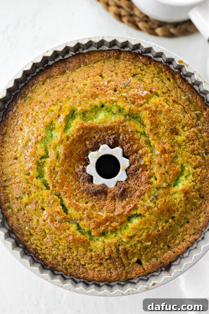 A freshly glazed Lemon Lime Bundt Cake, still in its pan, showing the initial layer of glaze soaking in.
