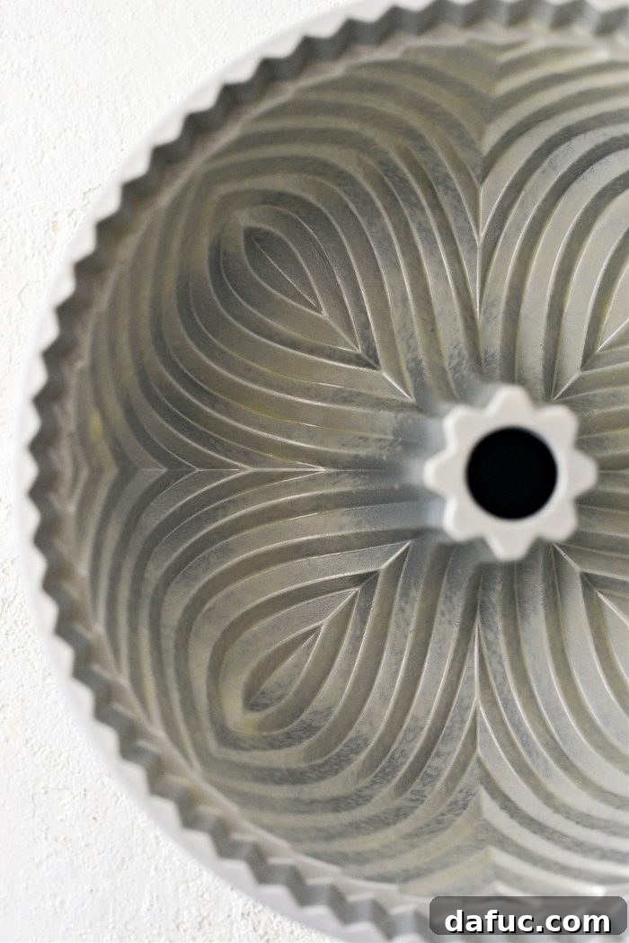 Close-up image of a bundt pan being prepped with butter and flour, showing the importance of proper greasing.