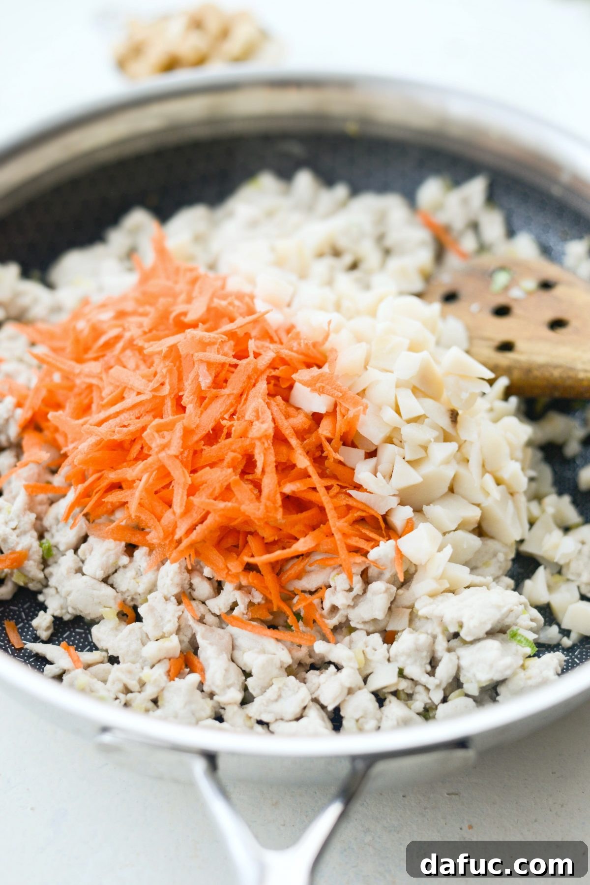 Vibrant Ginger Cashew Lettuce Wraps 7 Cooked ground turkey, shredded carrot, and chopped water chestnuts in a pan