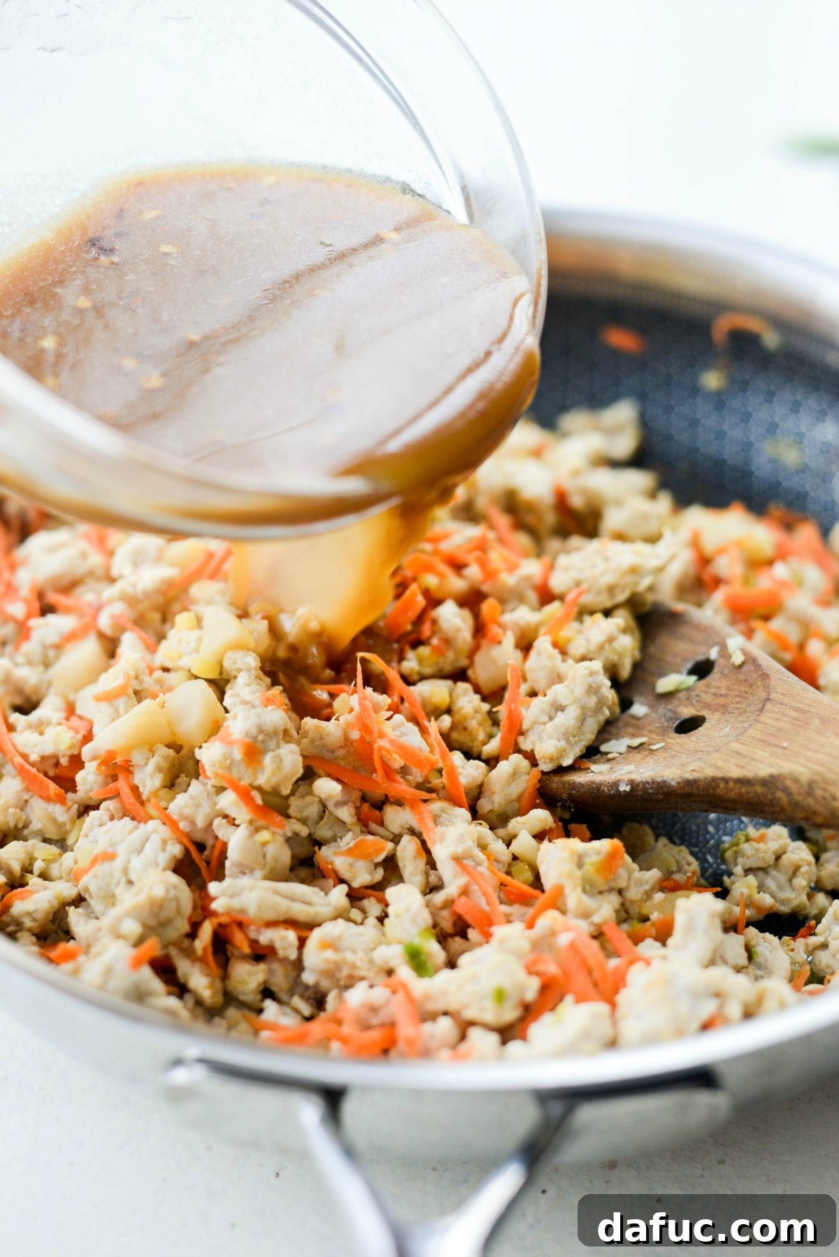 Vibrant Ginger Cashew Lettuce Wraps 9 Pouring the prepared sauce into the skillet with the turkey filling
