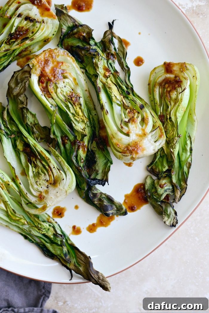 Close-up of a single portion of dressed baby bok choy on a plate, glistening with the homemade ginger chili sauce