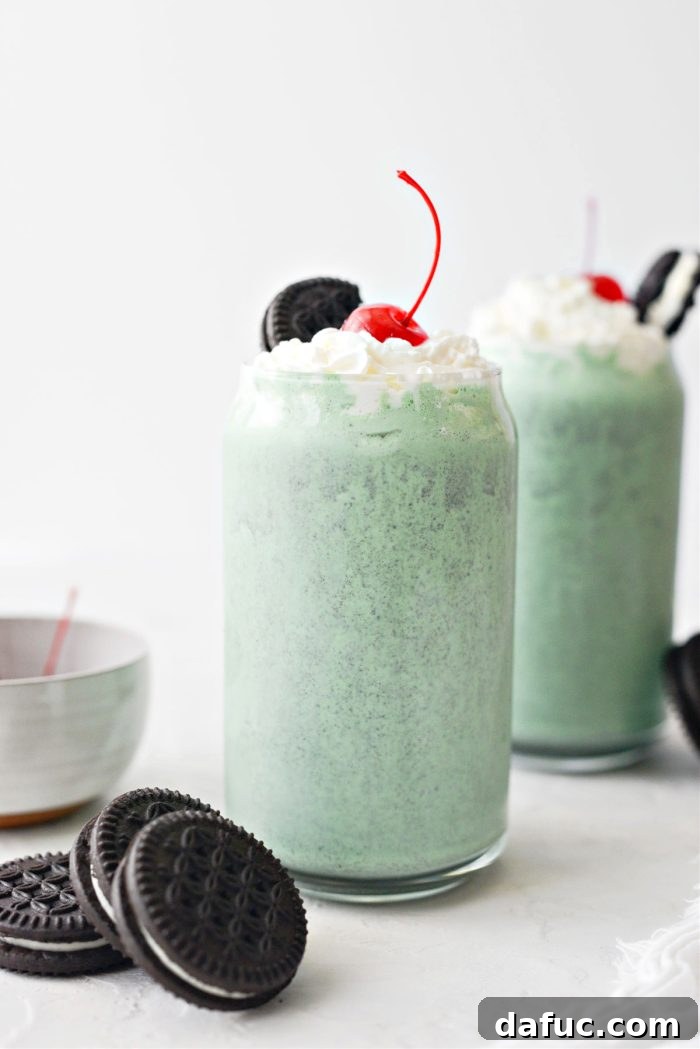 A tall glass of Cookies and Cream Shamrock Shake with whipped cream and a cherry