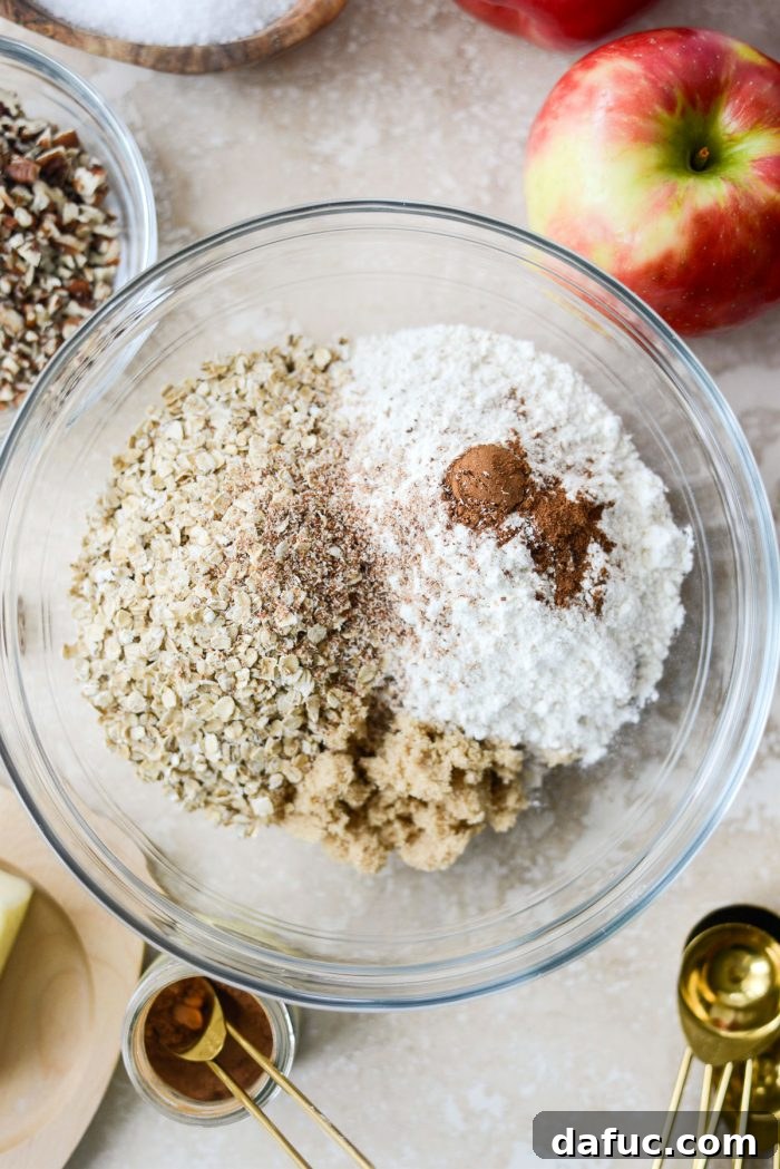 Effortless Apple Crumble 5 Sugar, quick cooking oats, all-purpose flour, ground cinnamon, ground nutmeg, and a pinch of salt in a glass mixing bowl.