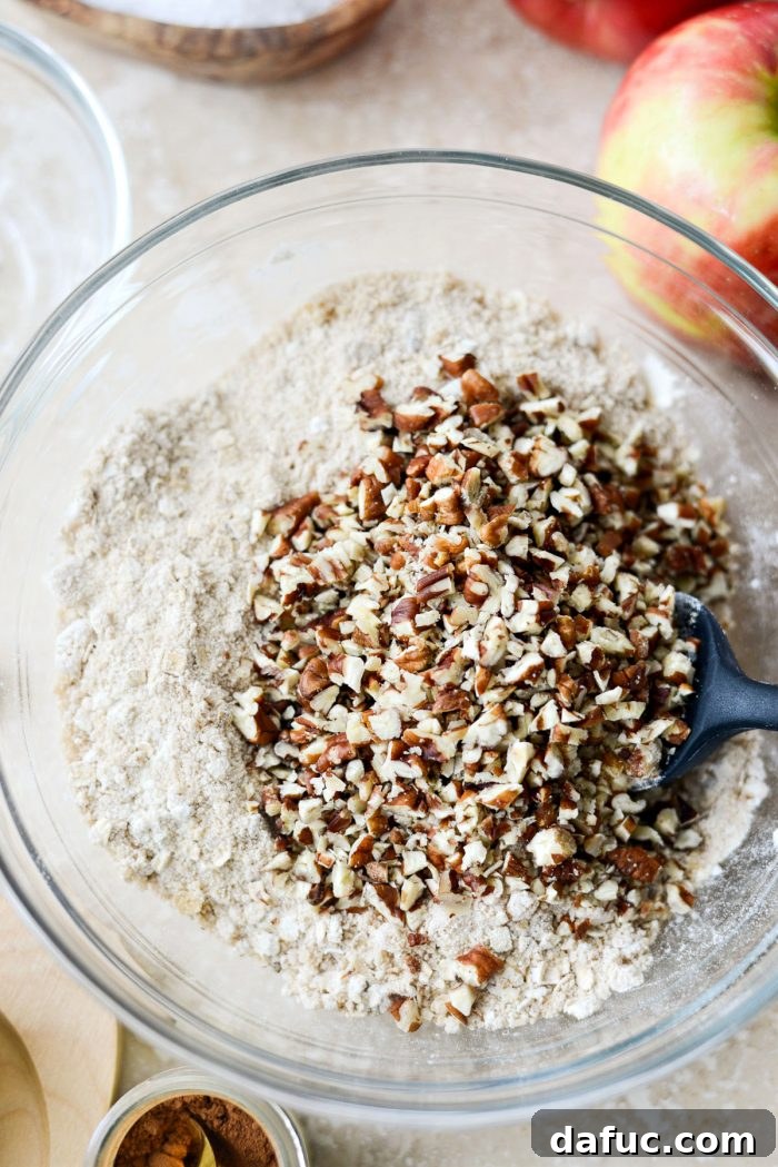Effortless Apple Crumble 6 Finely chopped pecans being added to the dry topping ingredients in a glass mixing bowl.