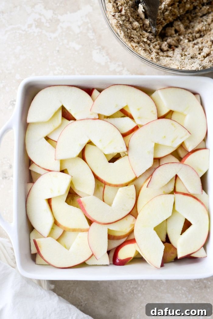 Effortless Apple Crumble 10 Sliced apples arranged neatly in an 8x8 or 9x9 baking dish, ready for the topping.