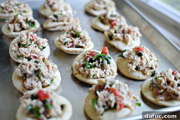 filled up Mini pita breads filled with tuna mixture on a baking sheet.