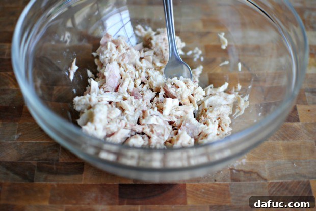 flaked Flaked albacore tuna in a mixing bowl, broken up with a fork.