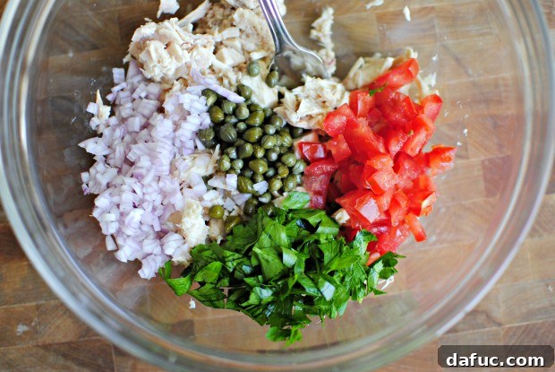add the rest Mixing bowl with flaked tuna, diced shallots, tomatoes, parsley, and capers.