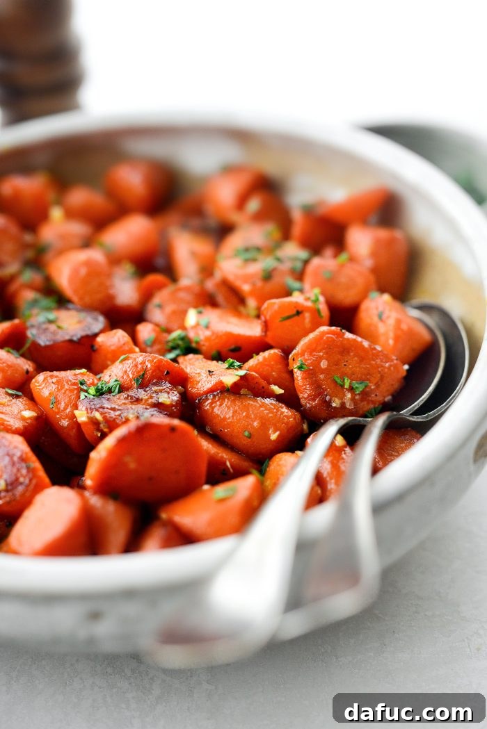 Overhead shot of Maple Glazed Carrots in a white bowl, with cooking utensils nearby