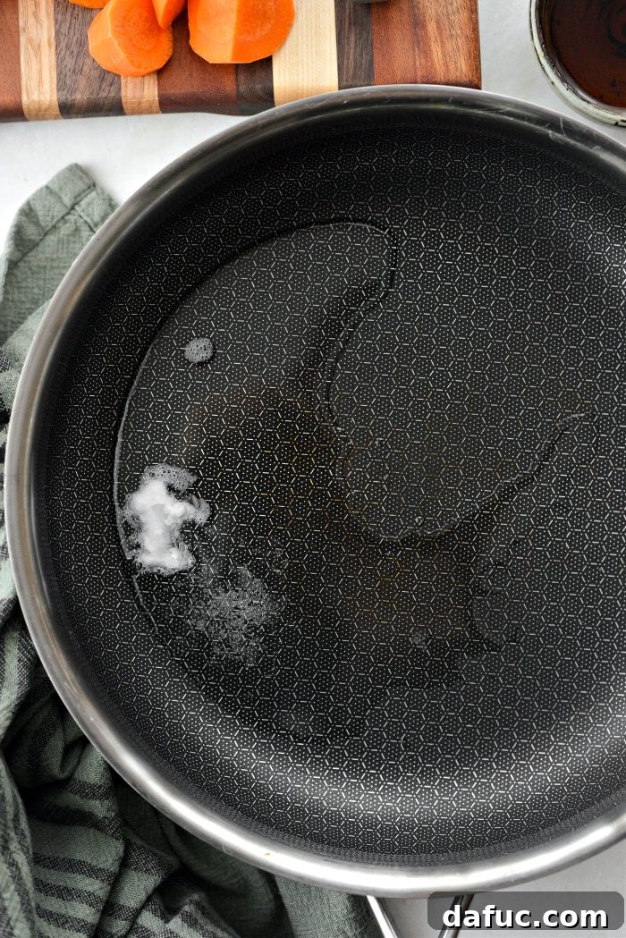Coconut oil melting in a large stainless steel skillet over medium heat
