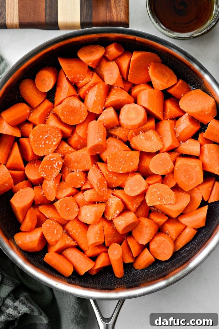 Adding roll-cut carrots and kosher salt to the melted coconut oil in the skillet