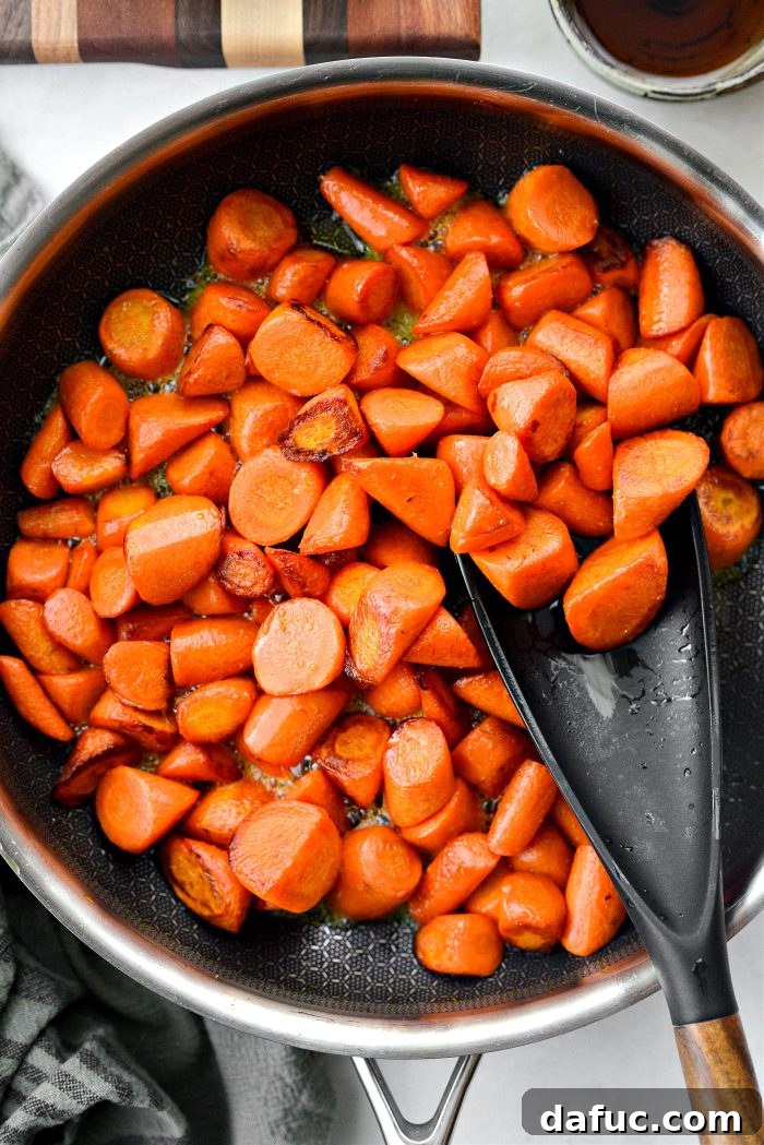 Carrots being tossed and cooked in a skillet, showing early stages of caramelization