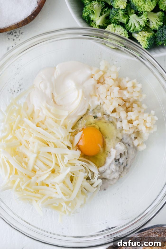 Cozy Broccoli Bake 6 Cream of mushroom soup, mayonnaise, baby swiss, water chestnuts, and an egg in a bowl