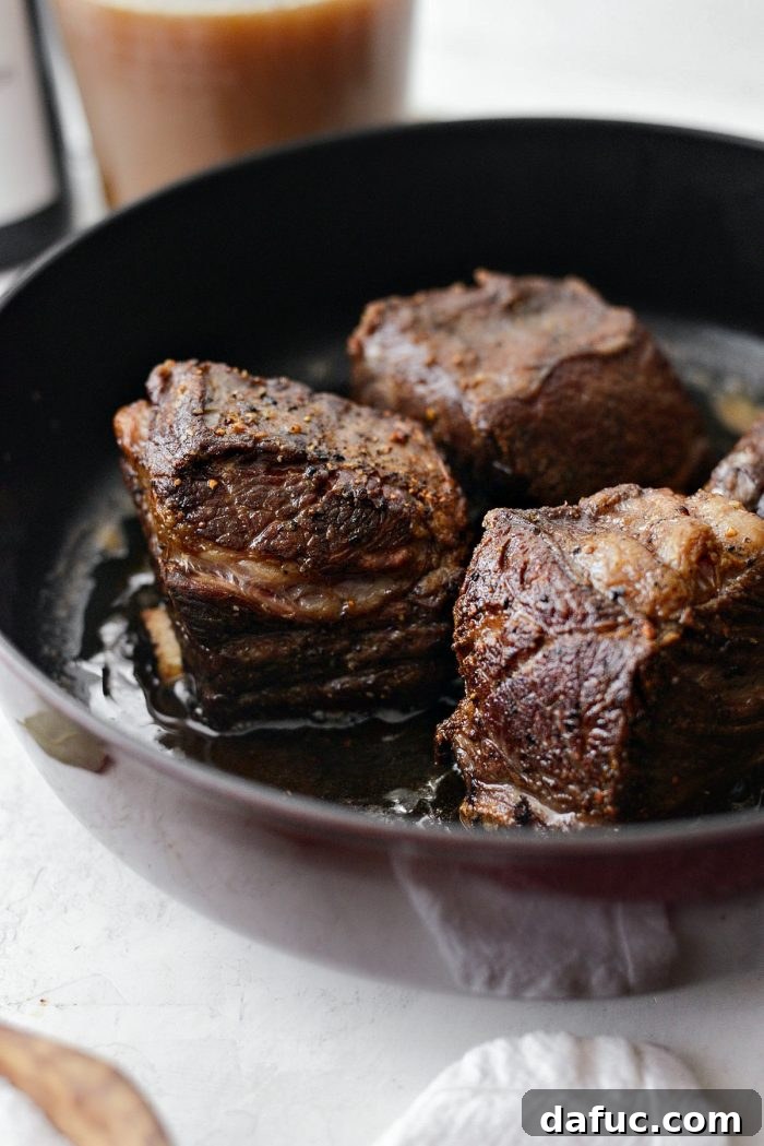Slow-Braised Beef Short Ribs 8 A close-up view of beef short ribs perfectly seared on all sides, displaying a desirable crispy, brown crust.