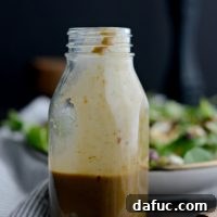 Sweet Basil Vinaigrette in a jar with fresh basil leaves for garnish