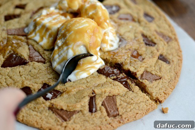 Two spoons digging into the warm double chocolate chunk share cookie with ice cream and caramel