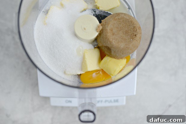 Dark brown sugar and granulated sugar added to the food processor with butter
