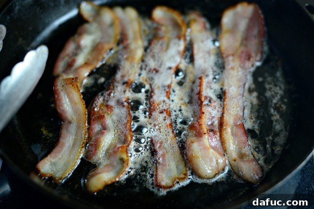 Cooking thick-cut applewood bacon in a skillet until crispy