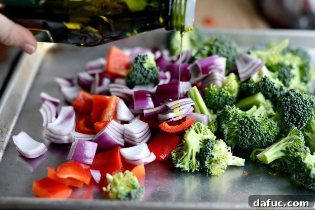 Sweet & Tangy Teriyaki Chicken Bowls 6 Veggies on a baking sheet - broccoli, red pepper, and onion ready for roasting