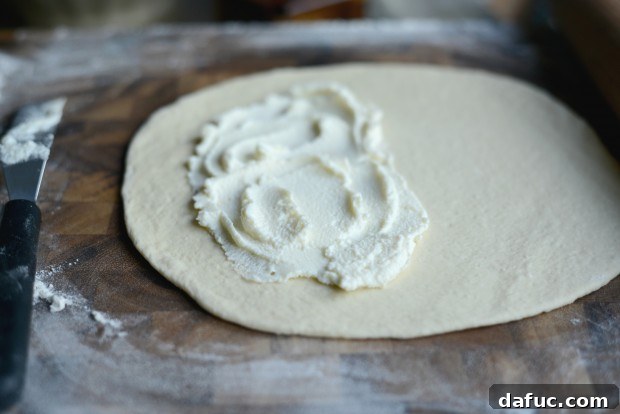 Spreading ricotta cheese on pizza dough
