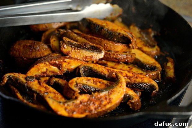 Cooking seasoned portobello mushrooms in a skillet