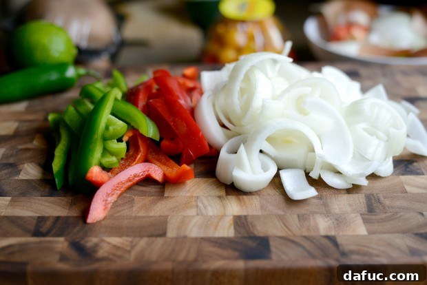 Sliced red bell pepper, green bell pepper, and yellow onion ready for cooking