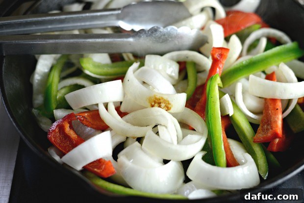 Bell peppers and onions sizzling in a cast iron skillet for fajitas