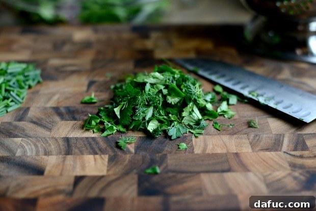 Shaved Raw Sweet Potato and Creamy Avocado Salad with Miso Dressing 11 Chopping fresh herbs (dill, parsley, cilantro) to be mixed with spring greens for a flavorful salad base.