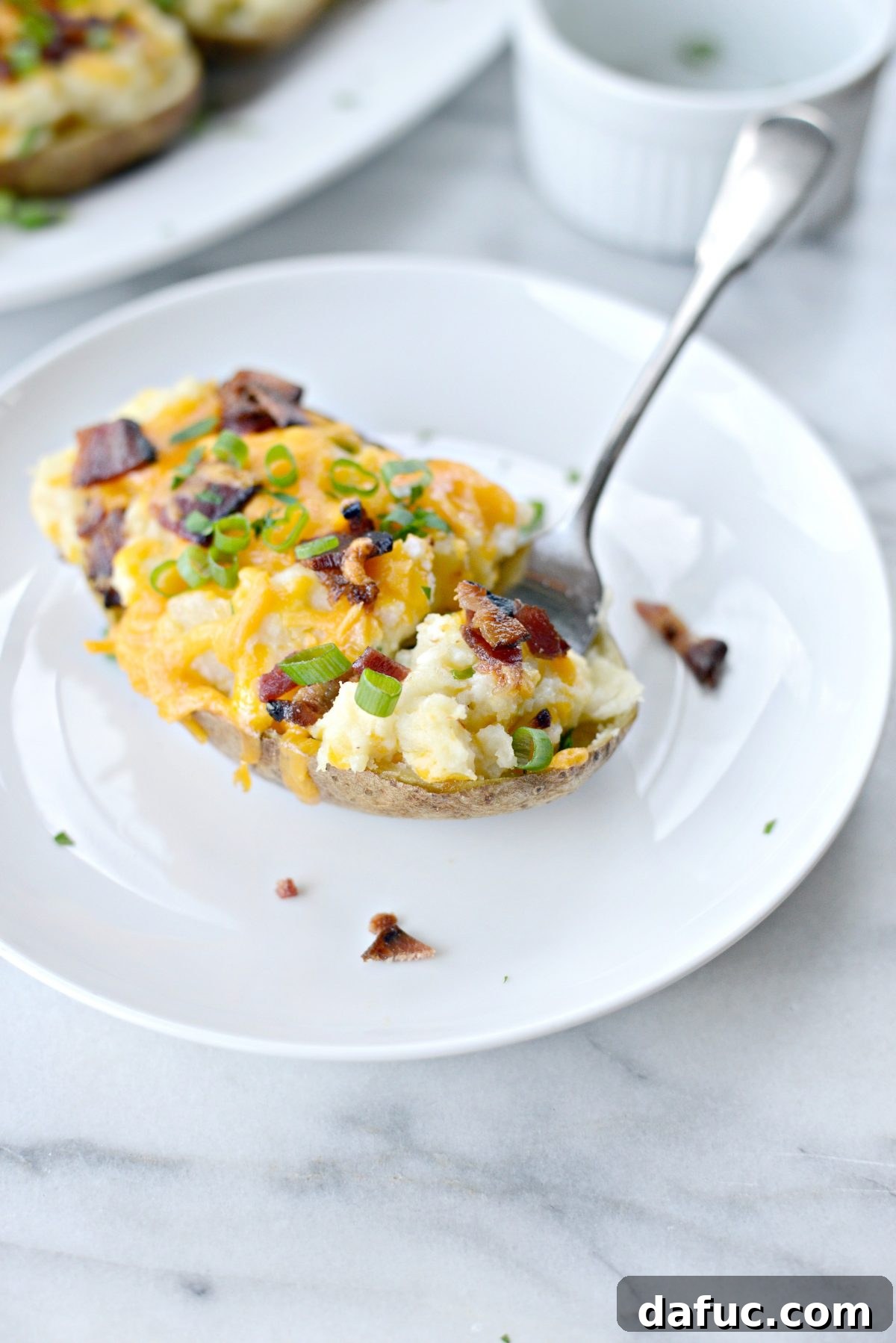 Decadent Double-Baked Potato Delight 14 A serving of Loaded Twice Baked Potatoes on a plate, garnished with fresh herbs